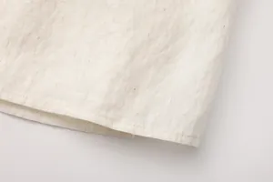 Detailopname van de gestikte zoom van een beige katoen-linnen maxi-rok van stof