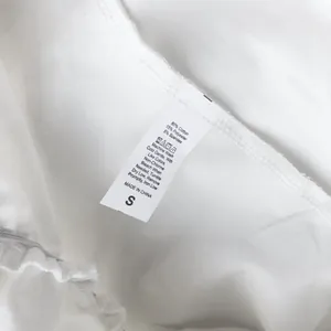 Etiqueta de cuidado en una falda blanca de talle alto con volantes y 80% de mezcla de algodón