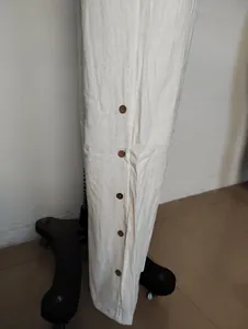Primo piano dei bottoni in legno su una tuta in lino beige con gamba larga per donna