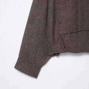 Close-up detail of a brown herringbone bomber jacket sleeve with high-quality texture