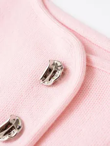 Primo piano di gilet rosa in maglia con bottoni argentati unici e trama raffinata.