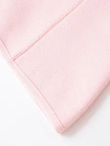 Dettaglio della trama del tessuto a maglia rosa tenue e delle cuciture di qualità sul bordo.