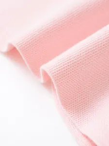 Dettaglio ravvicinato della morbida trama del tessuto in maglia rosa di un gilet estivo.
