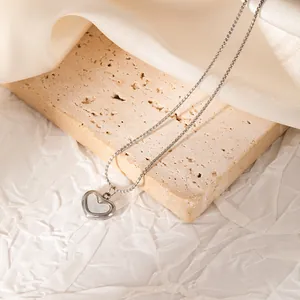 Vue détaillée d'un collier en acier inoxydable avec pendentif cœur et nacre blanche.