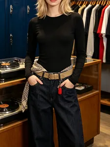 Black long sleeve slim fit bodysuit for women styled with jeans in a vintage shop