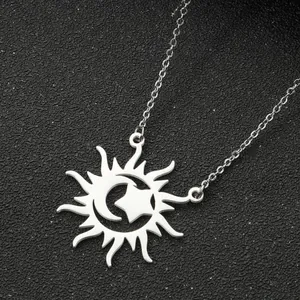 Close-up of a silver-tone sun, moon and star pendant necklace on a dark textured background