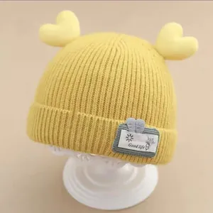 Detail view of a yellow knitted baby hat with cute heart-shaped decorations.