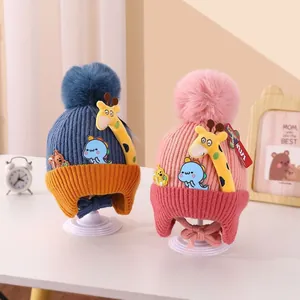 Detail view of two cute winter baby knitted earflap hats with giraffe and dinosaur cartoon decor