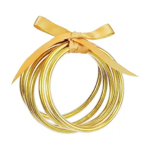 Elegante set di 5 bracciali in silicone glitterato oro con un fiocco in nastro