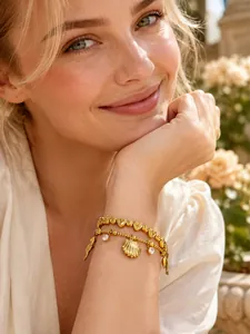 Détail du bracelet en acier inoxydable plaqué or avec pendentifs coquillage et dauphin