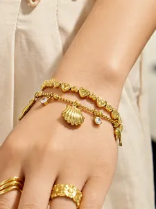 Gros plan d'un bracelet plaqué or 18k avec breloques coquillage, dauphin et cœur