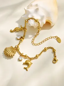 Détail d'un bracelet plaqué or 18 carats avec breloques coquillage, dauphin et cristal.