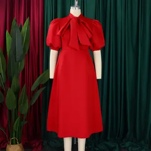 Détail de la robe de soirée rouge avec manches bouffantes, col noué et jupe évasée chic