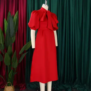 Détail d'une robe de soirée rouge avec un grand nœud papillon et des manches bouffantes