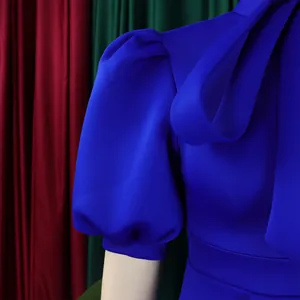 Gros plan d'une robe de soirée bleu roi avec manches bouffantes et un nœud élégant.