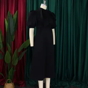 Robe midi noire élégante avec manches bouffantes et grand nœud sur un mannequin de couture.