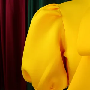 Gros plan sur la manche bouffante structurée d'une robe de soirée jaune vif élégante