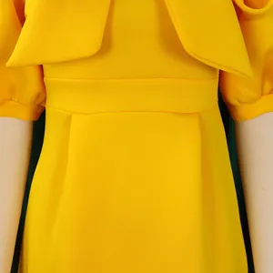 Gros plan détaillé de la robe de soirée jaune élégante avec corsage à nœud et taille.