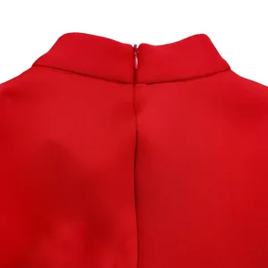 Gros plan sur le col montant et la fermeture éclair invisible d'une robe de soirée rouge.