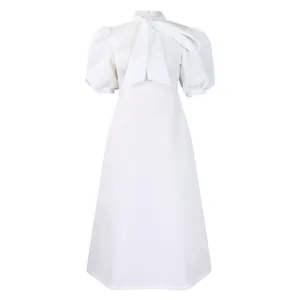 Gros plan sur le col à nœud élégant et le design des manches bouffantes de cette robe blanche