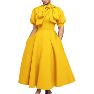 Détail rapproché d'une robe midi jaune vif avec un grand nœud papillon au cou