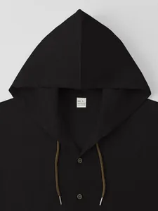 Detailed shot of black hooded cotton shirt showing fabric texture and neck tag