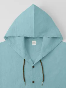 Macro detail showing the hood and neckline texture of a blue cotton linen shirt