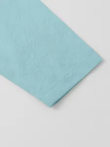 Close-up detail of natural linen-cotton fabric texture and stitching on light blue shirt sleeve