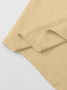 Close-up of beige cotton linen fabric texture and stitching detail of a men's shirt.
