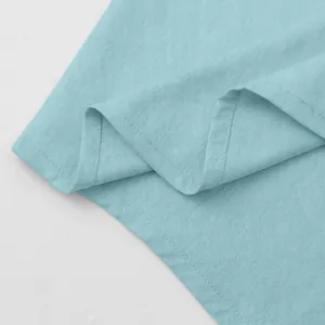 Macro detail of light blue cotton linen fabric showing fine weave and shirt hem stitching