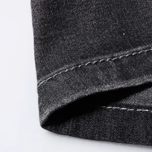 Detailed macro view of high-quality stitching on dark grey stretch denim jeans fabric