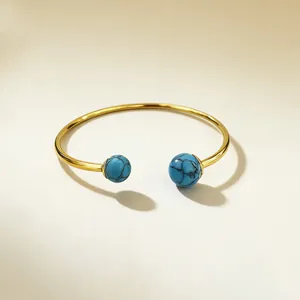 Detailed close-up of gold-plated open cuff bracelet featuring turquoise stone beads