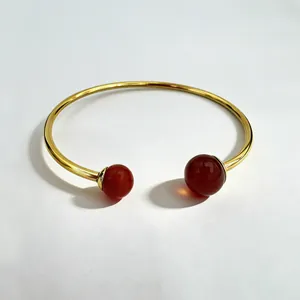 Detail view of 18K gold-plated stainless steel cuff bracelet with red spherical stones
