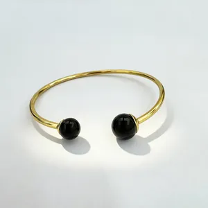 Detail view of a luxury 18K gold plated stainless steel cuff bracelet with black onyx beads