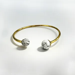 Close-up of gold stainless steel cuff bracelet with white marble stone beads detail