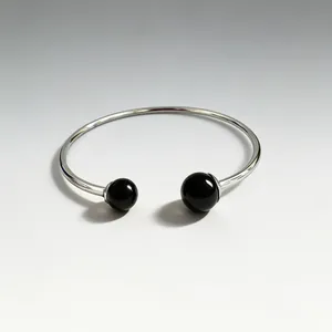 Detail view of a silver-toned stainless steel open bangle with black spherical stones