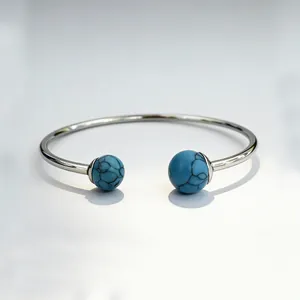 Detailed view of a stainless steel cuff bracelet featuring two blue turquoise stones
