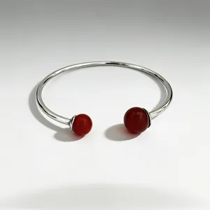 Detailed macro view of a silver stainless steel bangle with red spherical gemstone accents
