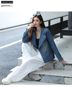Vue en pied d'un mannequin portant un blazer en jean bleu avec un pantalon blanc dehors.