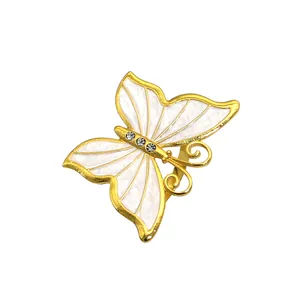 Dettaglio dell'elegante portatovaglioli a farfalla dorata con smalto bianco e strass