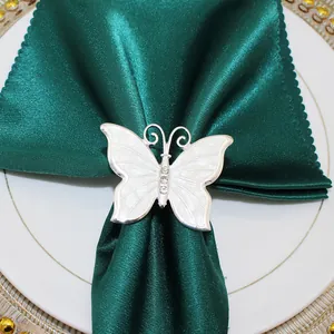 Dettaglio di un elegante portatovaglioli a farfalla bianca su un panno di raso verde