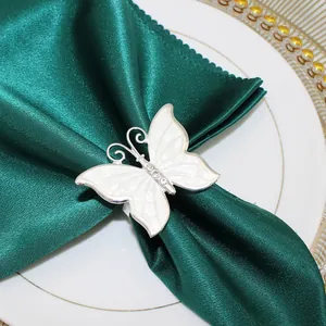 Dettaglio portatovagliolo a farfalla crema con cristalli su elegante raso verde scuro