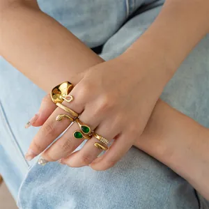 Detailed close-up view of multiple gold stainless steel rings worn on a model hand over denim.