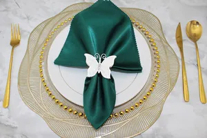 Dettaglio elegante di un portatovaglioli a farfalla in lega bianca su un tovagliolo verde