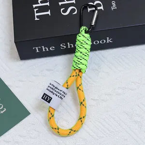 Primo piano di un cordino intrecciato a rete verde neon e giallo con moschettone nero.
