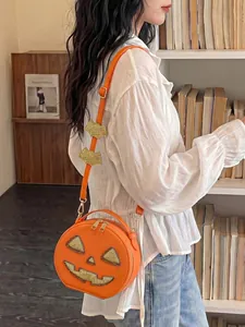 Detail of creative orange Halloween pumpkin crossbody bag with glitter eyes and bat strap.