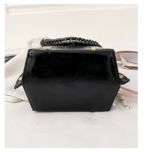 Vista dettagliata del fondo di una piccola borsa nera con motivo coccodrillo e borchie dorate