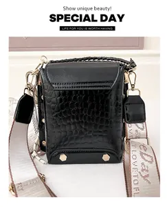 Primo piano di una borsa a tracolla nera a coccodrillo con ampia tracolla moda