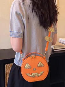 Close-up of orange Halloween pumpkin crossbody bag with sparkling gold accents and bat strap.