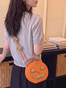 Close-up of a creative Halloween pumpkin crossbody bag with glitter accents and bat strap.